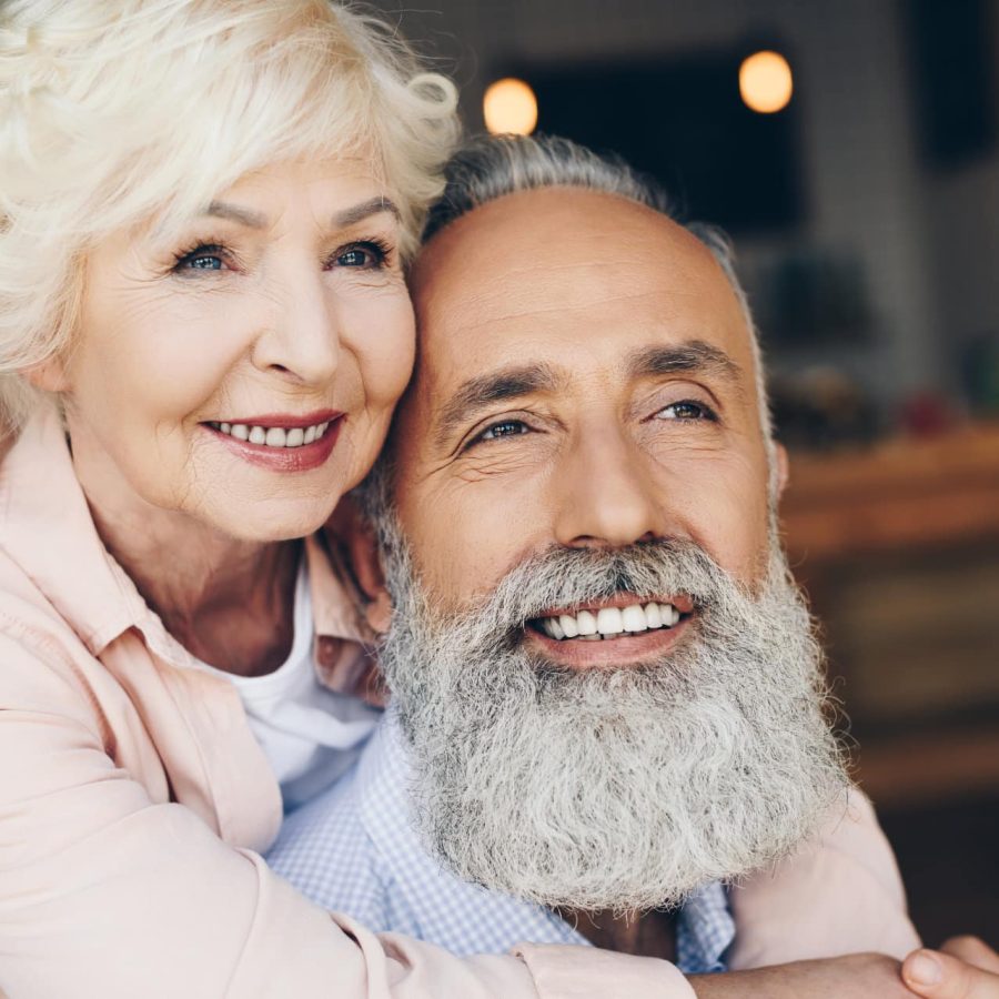 portrait of smiling senior woman hugging husband in cafe